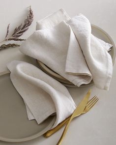 a white plate topped with two napkins next to a gold fork and silverware