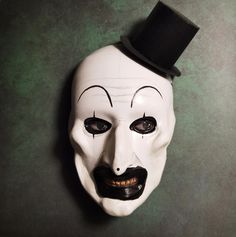 a white mask with black eyes and a top hat