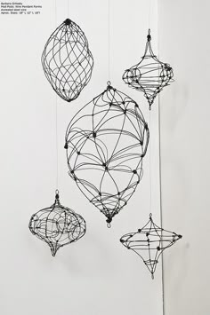 three wire ornaments hanging from strings on a white wall in an art gallery or studio