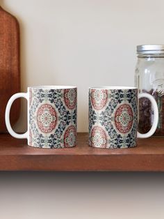 two coffee mugs sitting on top of a wooden shelf next to a mason jar