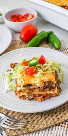 a white plate topped with lasagna covered in cheese and veggie toppings