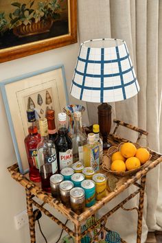 a table topped with bottles and oranges next to a framed painting on the wall