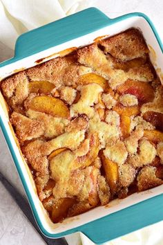 a casserole dish filled with peaches on top of a white table cloth