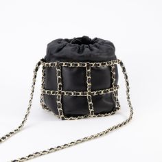 This lambskin bucket bag features a golden chain harness, shoulder strap, and drawstring closure. Luxury Chain Pouch Bag, Soft Leather Evening Bucket Bag, Luxury Bucket Bags With Chain Strap, Evening Shoulder Bag With Gold-tone Hardware In Bucket Shape, Luxury Chain Strap Bucket Shoulder Bag, Luxury Chain Strap Pouch Shoulder Bag, Luxury Shoulder Bag With Chain Strap, Evening Soft Leather Bucket Bag, Leather Bucket Bag For Party