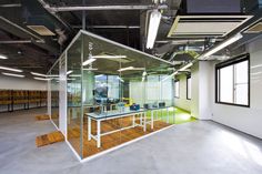 an empty office with glass walls and wooden flooring is pictured in this image from the inside