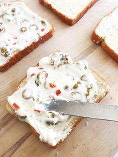 someone is spreading cream cheese on top of toasted bread with mushrooms and olives