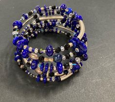 Handcrafted by one of our local artists this memory wrap bracelet is made with blue lapis , Swarovski crystals (which at times reflect a baby blue color), faceted onyx, sterling silver tube beads, and others. It is a one-of-a-kind harmonious fusion.  Blue lapis gemstone is sometimes referred to as "the wisdom keeper", and represents serenity and truth. - Gemstone : Blue Lapis, Faceted Onyx - Metal : Sterling Silver Tube Beads - Bracelet Wrap: 6 - Bracelet Wrist Size: Small Blue Crystal Bracelet With Stackable Round Beads, Adjustable Blue Wire Wrapped Beaded Bracelets, Blue Wire Wrapped Bracelets With Round Beads, Blue Wire Wrapped Bracelet With Round Beads, Adjustable Blue Multi-strand Wrap Bracelet, Adjustable Multi-strand Blue Wrap Bracelet, Blue Spiritual Stackable Beaded Bracelets, Adjustable Blue Stackable Wrap Bracelet, Blue Stackable Wrap Bracelet As Gift