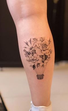 a woman's leg with flowers in a vase tattoo