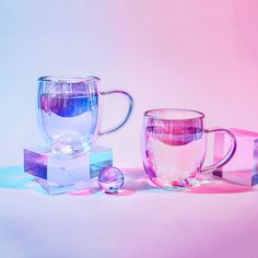 three glass mugs sitting next to each other on a pink and blue tablecloth