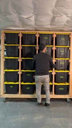 a man standing in front of a shelf filled with plastic bins and yellow tape