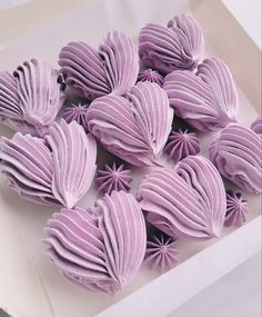 purple frosted heart shaped pastries in a white box on top of a table