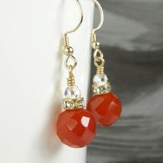 Gorgeous red orange hued faceted carnelian gemstones are an attractive dangle earrings. Handmade with high quality carnelian gemstones, very sparkly Swarovski crystal crowns, and a simple Swarovski crystal on top. A great gift for a woman who loves bold jewelry and bright orange hues. A great autumn accessory.Earrings Details:- Carnelian gemstones are 10 mm in diameter- Dangle earrings are 1.25 inches long (just over 3.17 cm)- Handmade with 14k gold filled wire and earring findings- Carnelian ea Carnelian Gemstone Dangle Earrings, Red Carnelian Jewelry With Faceted Beads, Carnelian Dangle Jewelry With Matching Earrings, Red Faceted Carnelian Jewelry, Faceted Carnelian Jewelry Gift, Carnelian Drop Earrings Jewelry Gift, Orange Carnelian Earrings For Gift, Elegant Carnelian Dangle Earrings, Nickel-free Red Carnelian Earrings