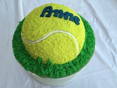 a tennis ball cake with green grass on the bottom and name ame on top