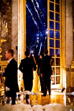 people standing in front of an open window with fireworks coming from the windowsills