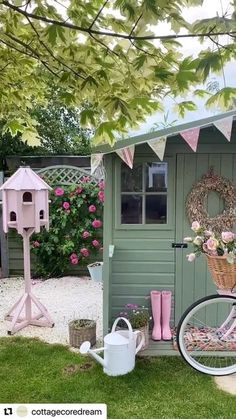 a bicycle parked in front of a green shed with flowers on the roof and pink boots