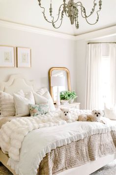 a bedroom with a bed, chandelier and two teddy bears on the bed