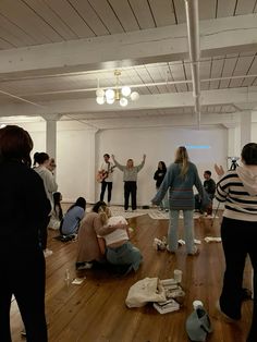 a group of people standing in a room with their hands up and one person sitting on the floor