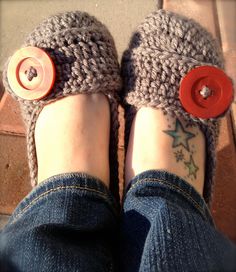 a person's feet with red buttons on them and their shoes covered in knitted slippers