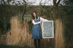 a woman holding up a sign in front of some tall grass