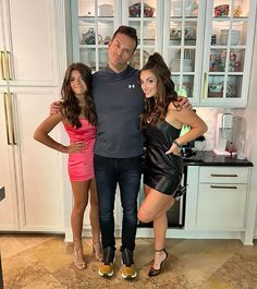 two women and a man are posing for a photo in the kitchen with their arms around each other