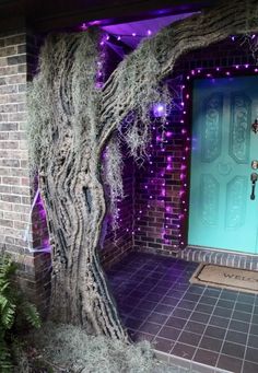 a door is decorated with purple lights and a tree in front of the house that has been decorated for halloween