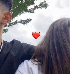 a man and woman standing next to each other with a red heart on their forehead