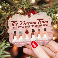 a hand holding up a christmas ornament with the names of five brides