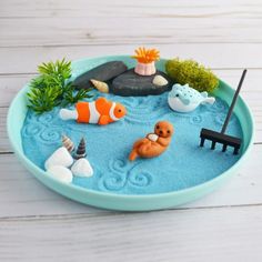 a bowl filled with toys on top of a white wooden table next to plants and rocks