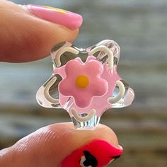 a woman's hand holding a pink ring with a flower on it