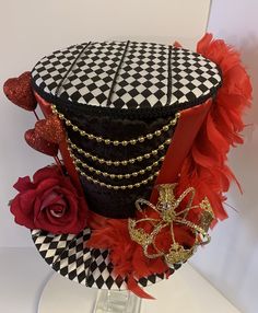 a black and white hat with red feathers on it, sitting on top of a table