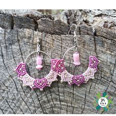 a pair of pink and white earrings on top of a piece of wooden planks