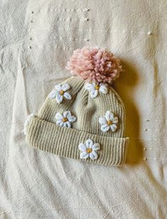 a knitted hat with flowers on it laying on a white sheet, top view