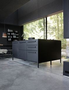 a black cabinet in the middle of a room with large windows and lots of furniture