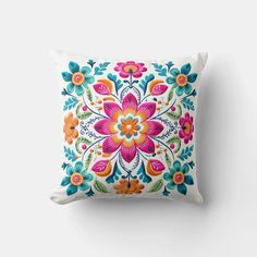 an embroidered pillow with colorful flowers on the front and back, sitting against a white wall