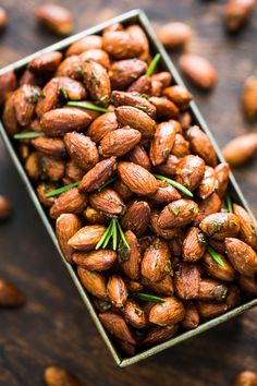 almonds with rosemary sprigs in a small box on a wooden table top