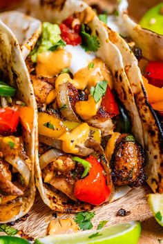 three tacos with chicken, peppers and onions on a cutting board