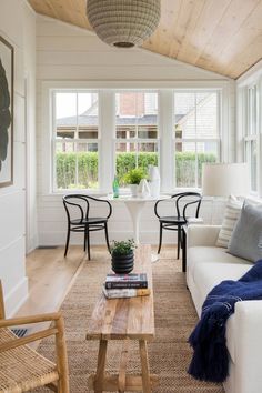 a living room filled with furniture and a wooden table in front of a large window