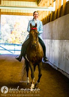 a woman riding on the back of a brown horse in an enclosed area with wooden walls