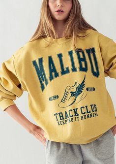 Introducing the Malibu Track Sweatshirt, a must-have for your spring/summer wardrobe. This long sleeve, garment-dyed piece features an oversized fit and bold "Malibu Track Club" graphic, perfect for adding a pop of color to your outfit. Stay on-trend... Spring Summer Wardrobe, Club Sweatshirts, New Tops, Contemporary Fashion, Logo Tees, Graphic Shirts, Summer Wardrobe, Denim Dress, Mustard