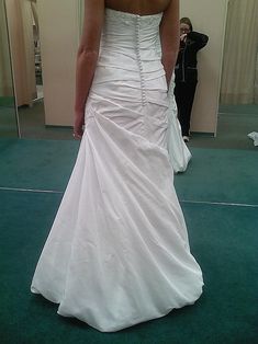 a woman in a wedding dress looking at herself in the mirror