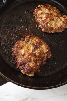 two hamburger patties cooking in a frying pan