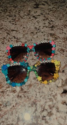 two pairs of sunglasses sitting on top of a marble counter covered in beads and flowers