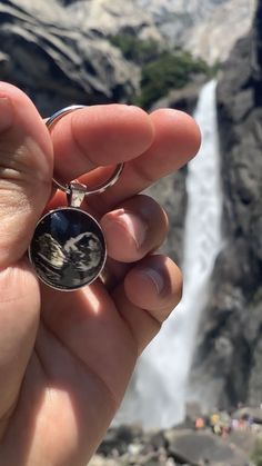 a person holding a ring in front of a waterfall