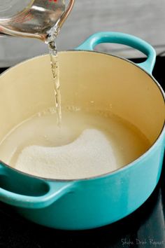 someone is pouring water into a blue pot