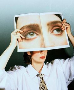 a woman holding up an open book to her face with the image of a person's eyes