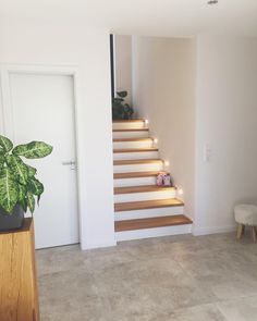 a living room with stairs leading up to the second floor and potted plant on the far side