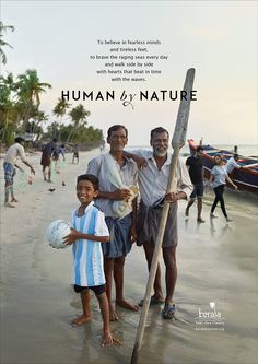 two men and a boy standing on the beach next to a pole with a sign that says human by nature