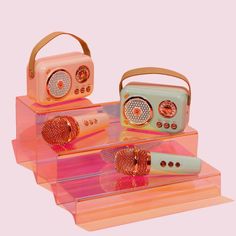 three different types of radio and hair dryer on acrylic trays with pink background