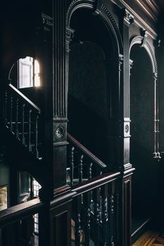 an ornate staircase in a dark room with light coming through the window