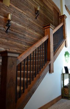 a wooden stair case next to a table with a plant on it and a clock hanging from the wall